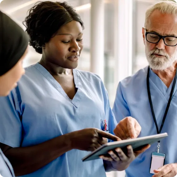 Üç sağlık uzmanı bir tablete bakıyor ve tartışıyor.